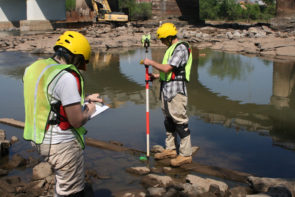 People taking measurements at a dam.